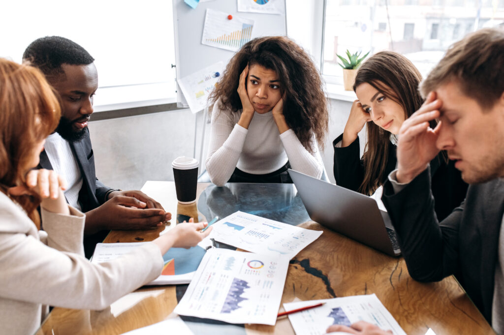 A group of business professionals appearing stressed out during a team meeting.
