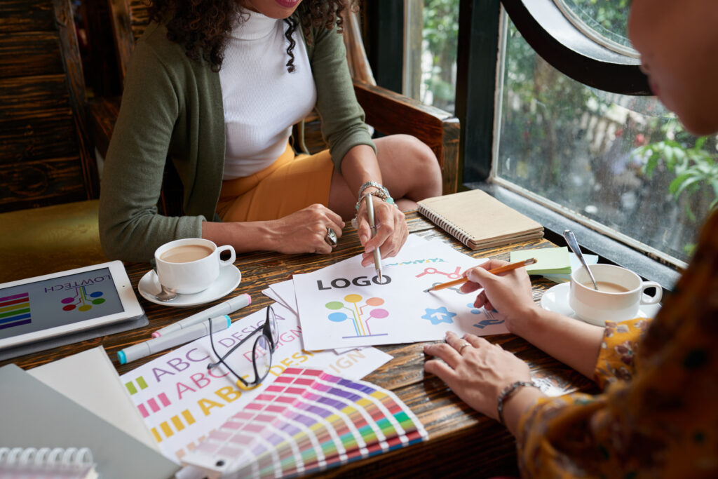 Two people sitting across from each other while working on a logo design